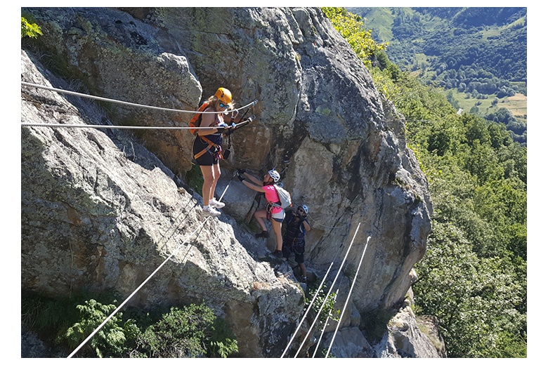 a person crossing the tibetan bridge on the poi d'unha via ferrata and two other about to do it