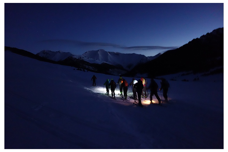 esquiadores de travesía aún de noche con los frontales encendidos emprendiendo la ruta hacia el Tuc de Barlonguèra.
