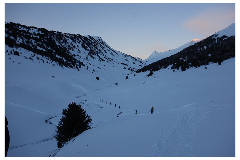 group of touring skiers at valle de parros, first sunlights of the day illuminating the summit of tuc de paaros