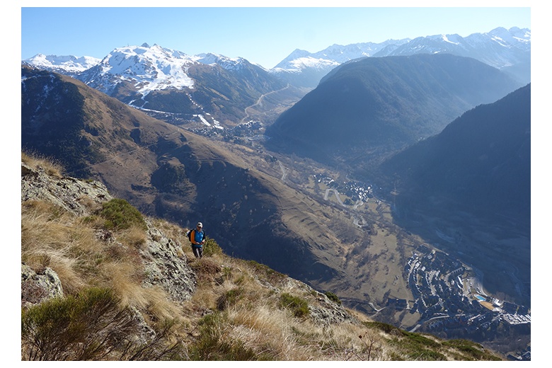 mountain walker after accomplishing the poi d'unha via ferrata on his way down to the village with an astonishing background. View of the val d'aran, villages of salardú, tredòs and baqueira-beret ski resort