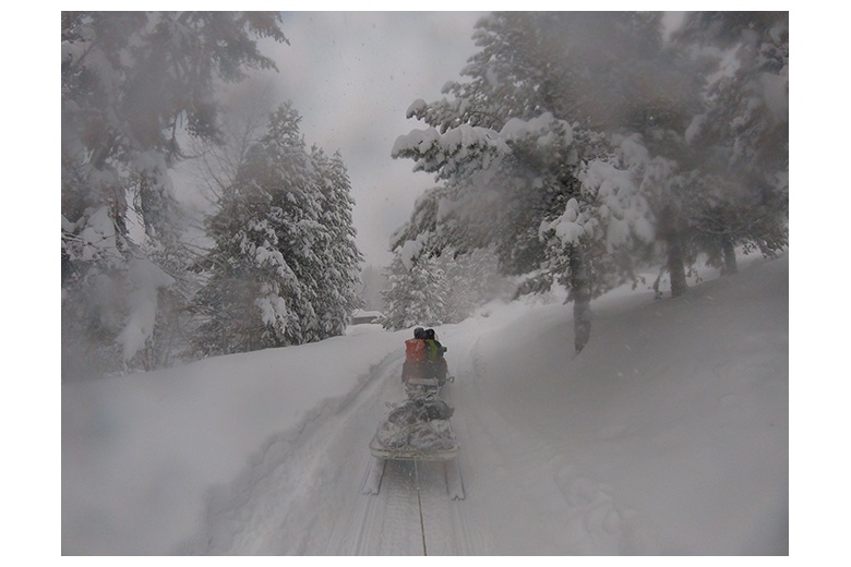 motoneige tire des skieurs vers le fond de la vallée d'aiguamòg au milieu d'une intense chute de neige