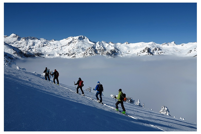 group of touring skiers in la peülla with an incredible sea of clouds and summits above it as a view