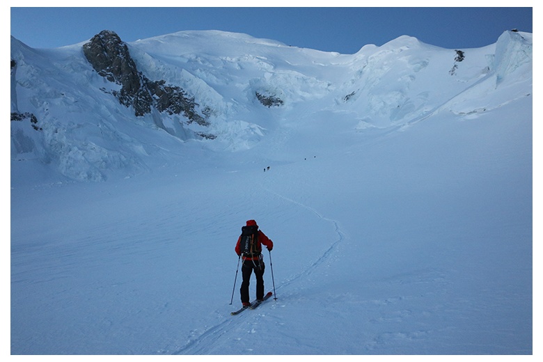 alpiniste en skis qui suit la trace au levé du soleil avec le sommet du mont blanc à sa portée d'yeux