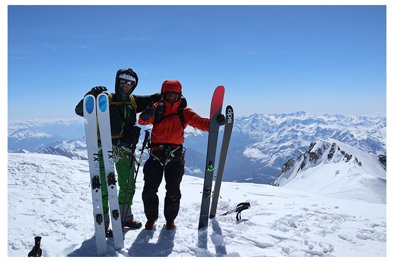 guía y cliente triunfantes en la cima del mont blanc con una de las espectaculares panorámicas a sus espaldas