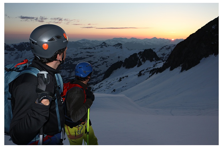 2 mountain skiers climbing the aneto at the maladeta mountain range admiring the sunrise 