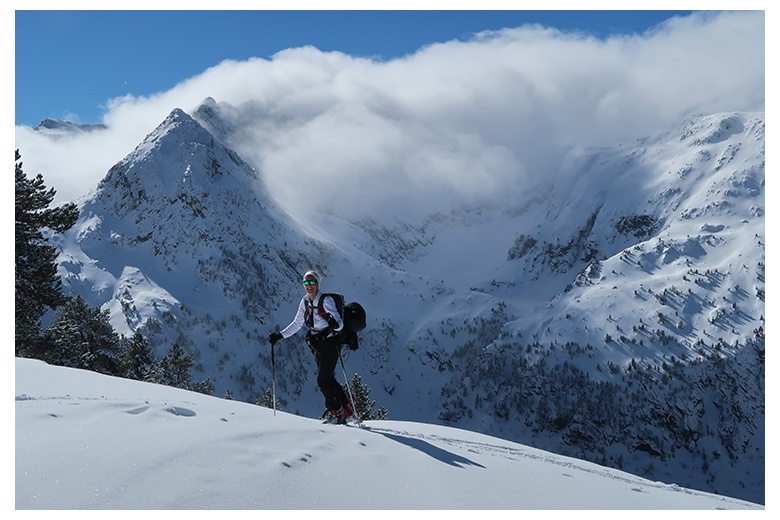 skieuse de randonnée en pleine ascension vers le sommet du tuc de salana, derrière le montardo couvert de nuages