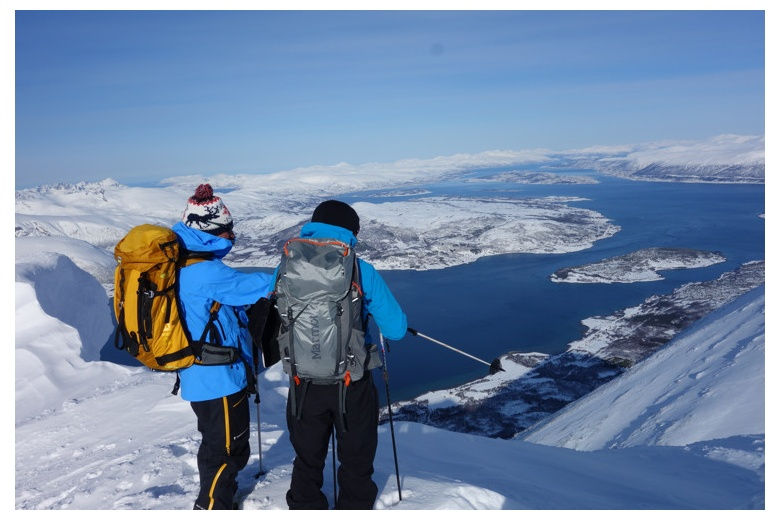skieurs au sommet de montagne en regardant vers la mer et la ville de Tromso