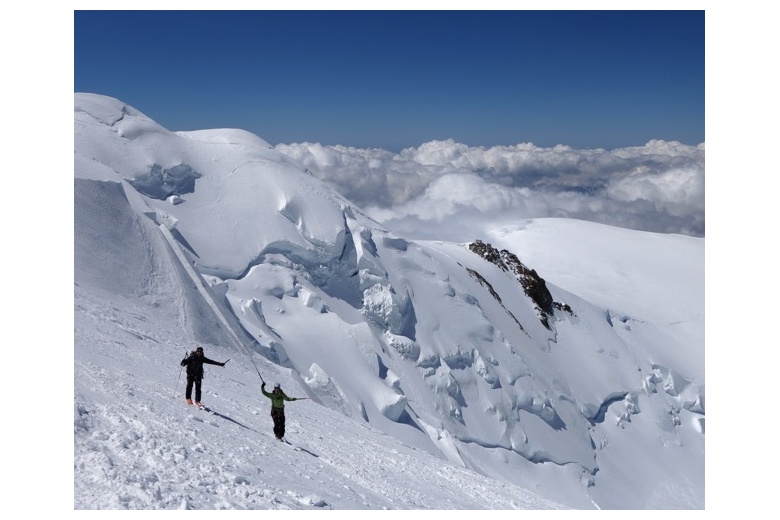 dos esquiadores de travesía ascendiendo hacia la cima del mont blanc