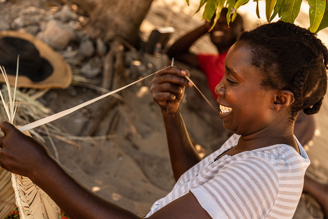 sonriente lugareña de la provincia de inhambane (mozambique) trabajando la hoja de palma