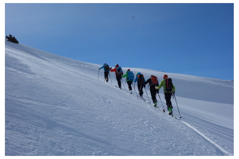 group of tour skiers ascending through a quite steep slope on their way to the goal of the day
