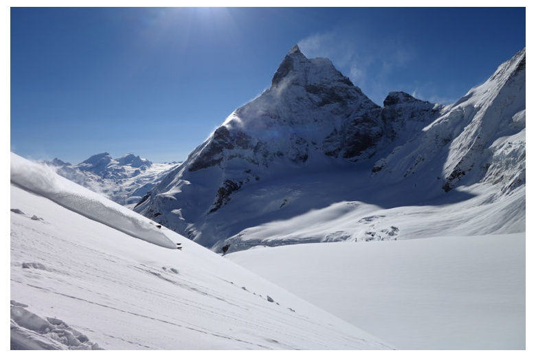 skier on fresh powder with cervino at the background skiing down to zermatt