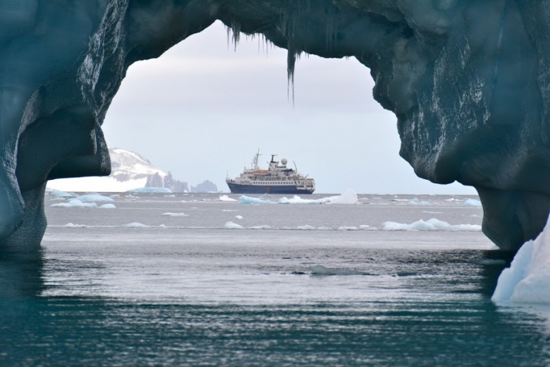 barco visto a traves de un arco formado por un iceberg