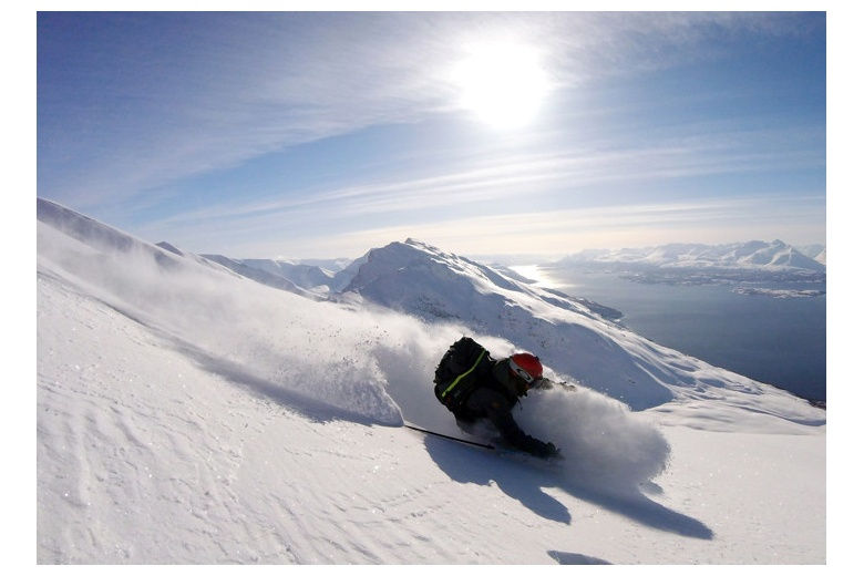 skiing down on superb powder snow on a perfect day of sun, sea on the background